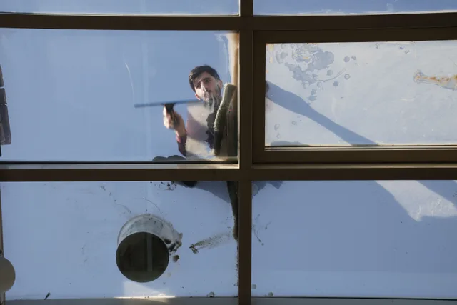 A male window cleaner washing the exterior glass roof from above with a tool during daylight. Window cleaning employee training checklist: five hands-on modules