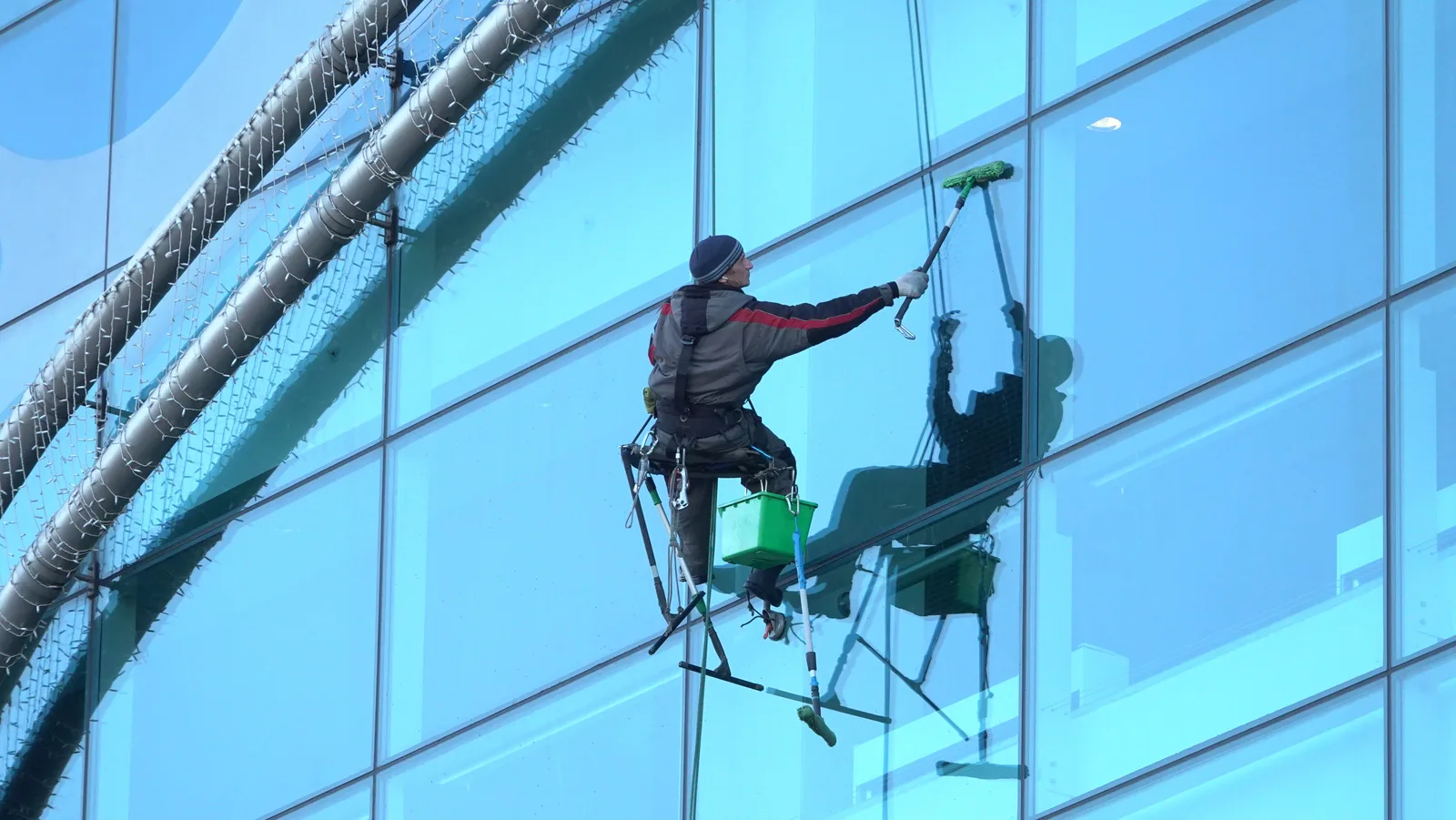 Window cleaner works on a high-rise glass building, ensuring spotless results. 9 points worth checking on window cleaning startup